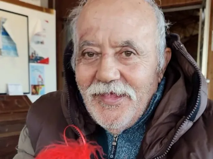 Un anziano sorridente mostra una pallina di Natale con la sua fotografia